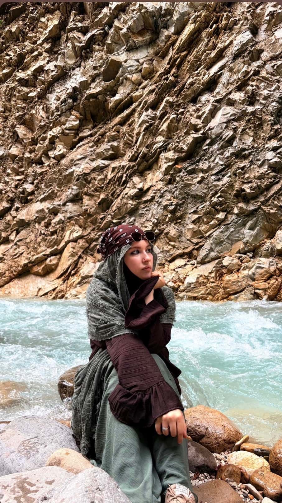 Amina sitting beside a mountain river